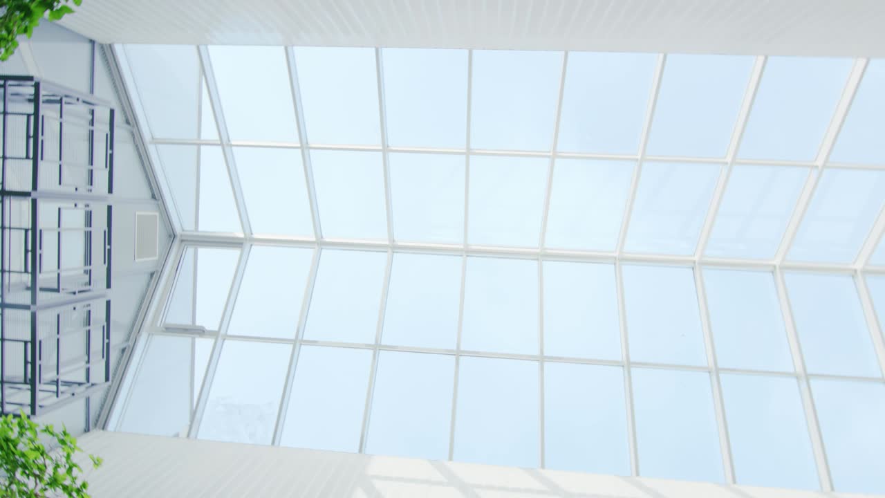 Low Angle Rotating Shot of the Glass Ceiling in the Hospital / Building / Mall/ Supermarket. Big White Building with Sun Rays Coming out of Windows.