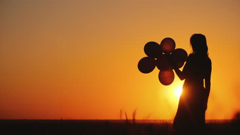 Silueta-De-Una-Mujer-Con-Globos-Al-Atardecer-Concepto-De-Nostalgia