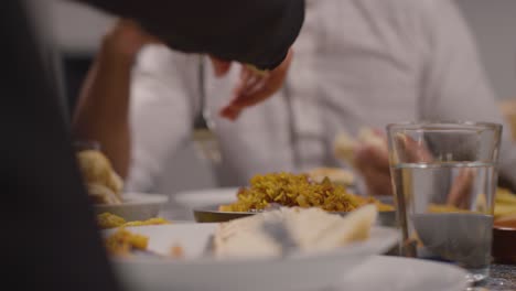 cerca de una familia musulmana sentada alrededor de una mesa en casa comiendo para celebrar el eid