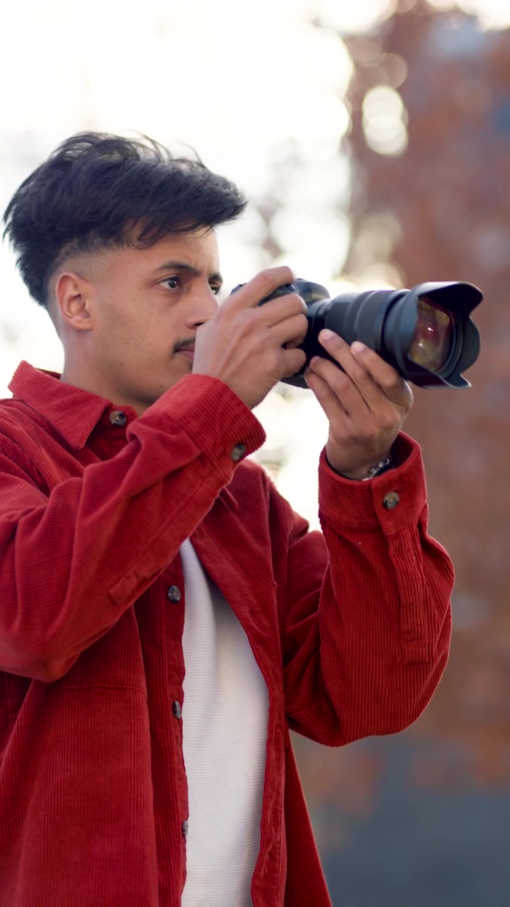 Giovane uomo che regola le impostazioni della fotocamera e scatta foto all'aperto
