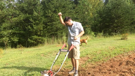 young man tilling garden in backyard