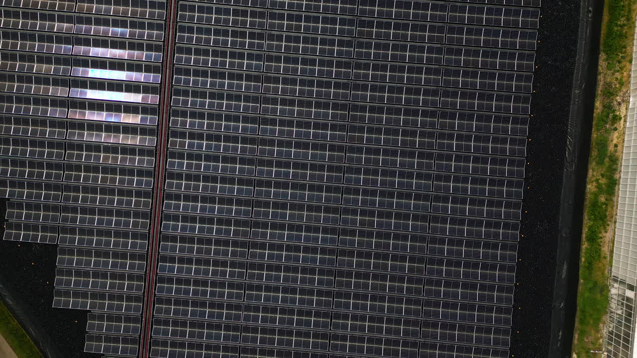 el sol se refleja en los techos de vidrio de los invernaderos masivos, vista aérea de arriba hacia abajo