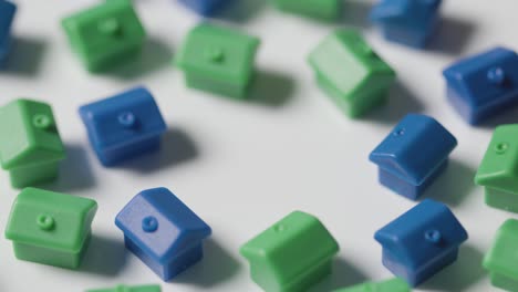 concepto de compra de vivienda con modelos de plástico azul y verde de casas que giran sobre fondo blanco