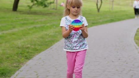 Children-girl-squeezing-presses-colorful-anti-stress-touch-screen-push-pop-it-popular-toy-in-park