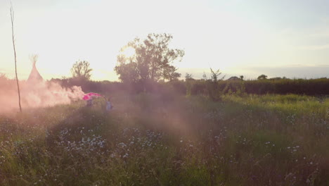 Dos-Amigas-Acampando-En-Un-Festival-De-Música-Corriendo-Por-El-Campo-Con-Bengalas-De-Humo