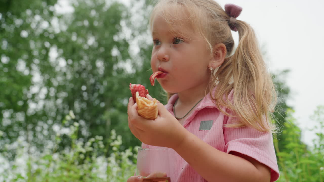 little girl tasting strawberry waffle outdoors, backyard picnic scene with greenery and sunlight tiny foodie sampling juicy berry, curious snacker examining texture, playful taste tester savoring