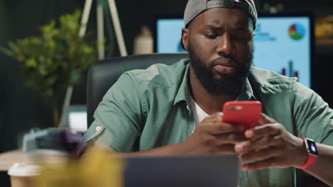 Closeup-young-african-american-man-typing-message-on-mobile-phone-in-office