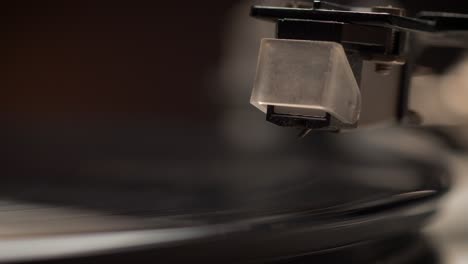 dropping stylus needle on vinyl record playing with disc rotating close up, macro