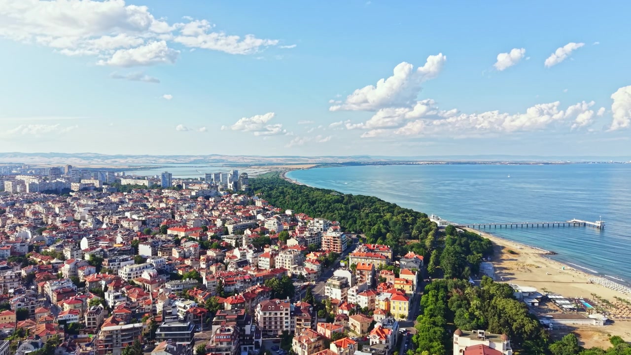 Vista costiera con il profilo della città e la spiaggia lungo il lungomare durante una giornata di sole.