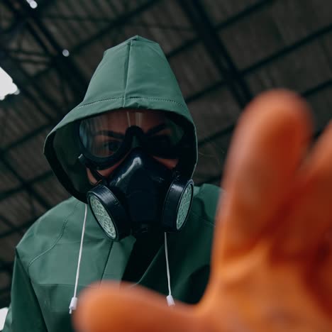portrait of a woman in safety suit and gas mask. human wearing antibacterial costume trying to touch something with hand in glove in abandoned place. gas attack