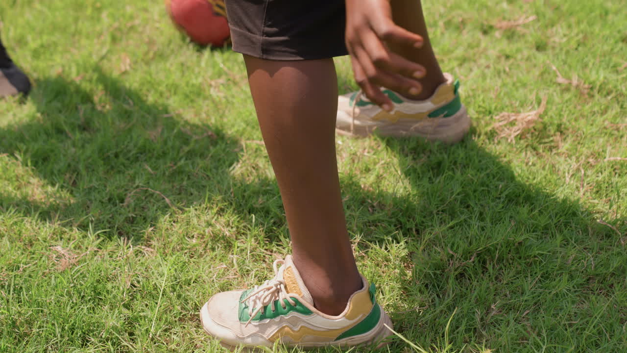 Giovane ragazzo con una palla rossa che gioca all'aperto. Bambino che si allena con un pallone da calcio in un cortile soleggiato. Giovane ragazzo che esegue abili esercizi di dribbling sull'erba durante una calda giornata estiva.