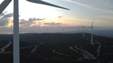 Breite-Luftaufnahme-Eines-Windparks-Mit-Kopierbereich,-Während-Sich-Eine-Turbine-In-Der-Nähe-Der-Kamera-Auf-Der-Linken-Seite-Dreht