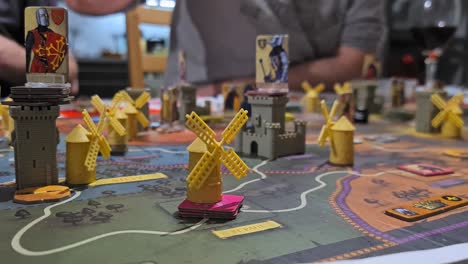 male hand puts a toy windmill on fief board game - close up shot