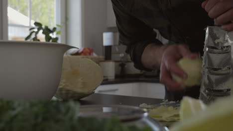 hombre triturando vegetales para fermentar en el mostrador de la cocina en casa, movimiento deslizante