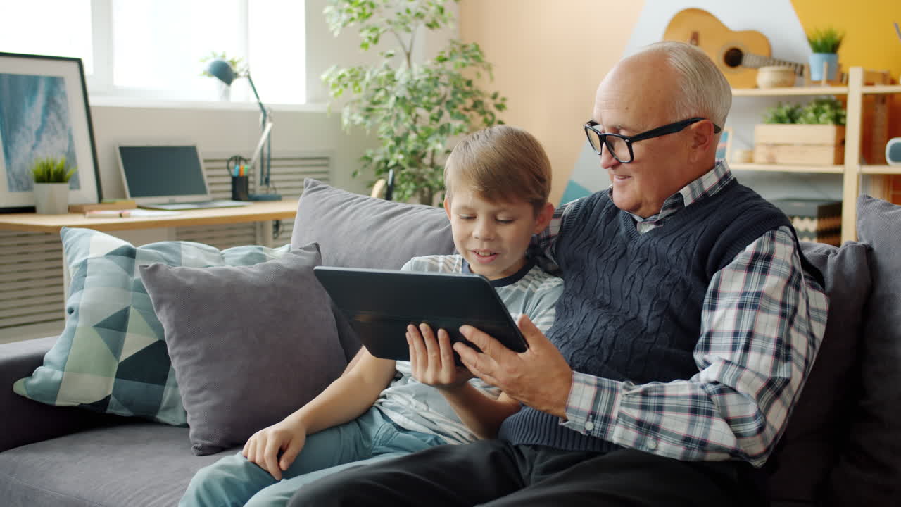 Grandfather and grandson using a tablet on the couch