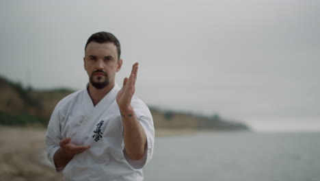 fit fighter training karate punches on beach. man learning combat techniques.