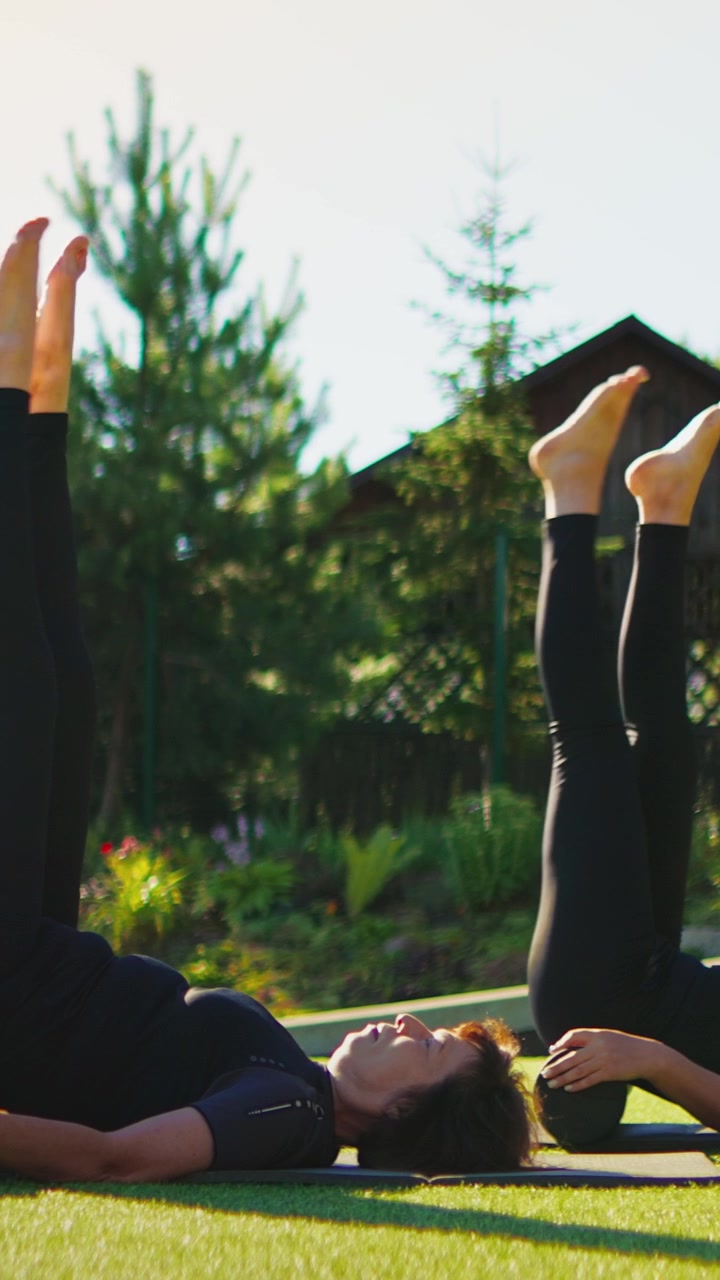 Two Women Practicing Pilates Exercises Outdoors on Yoga Mats