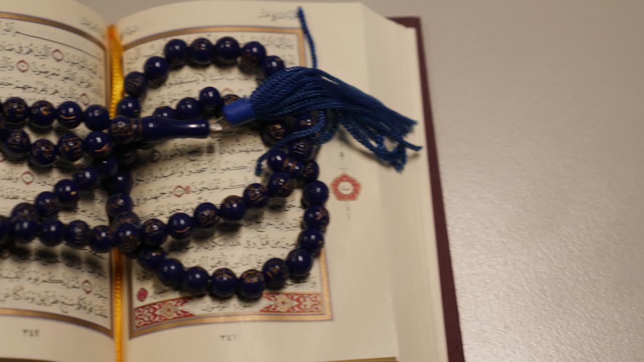 Moving shot of an open Quran lying on a table, the shot is moving from right to left side