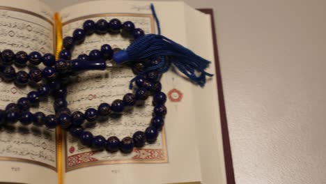 moving shot of an open quran lying on a table, the shot is moving from right to left side