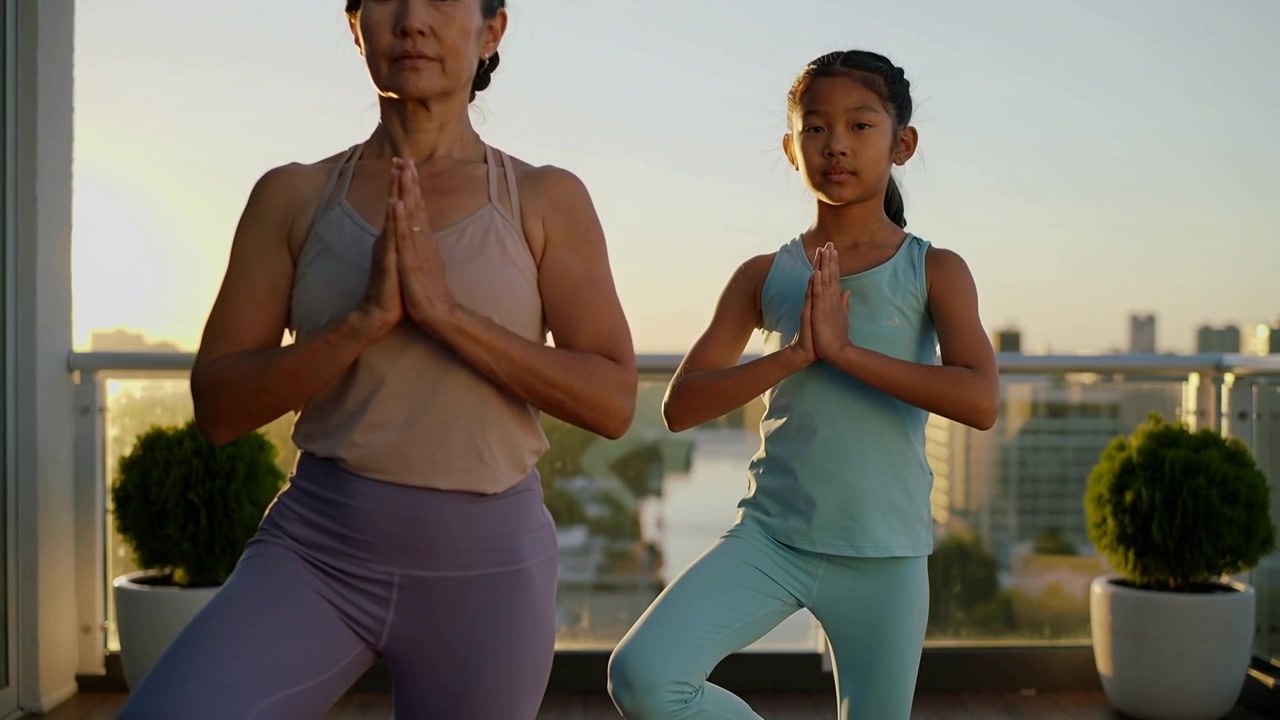 Practicing parent-child in activewear responding to sun holding tree-pose on balcony with railing