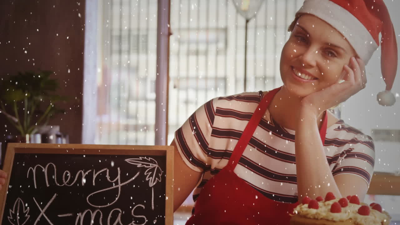 composición de video con nieve cayendo sobre chica feliz en sombrero de santa con pizarra en la tienda