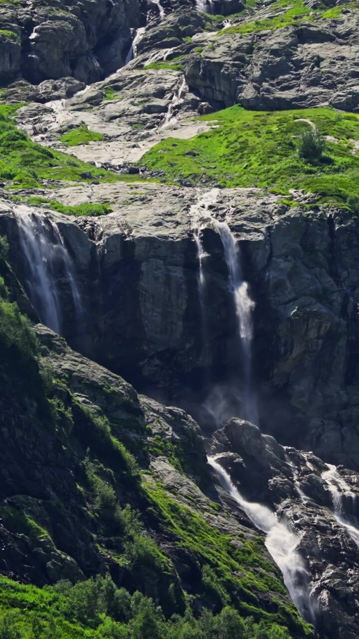 Molteplici cascate che scendono da una montagna rocciosa e verde