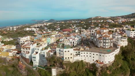 drone vuela lejos de un pueblo con una iglesia a través de un cañón en gran canaria
