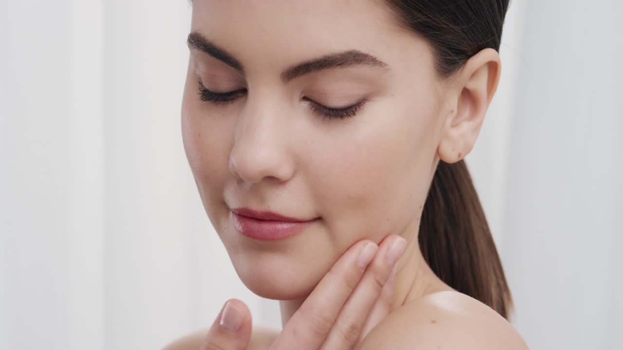 retrato de cerca de una mujer joven hermosa tocando suavemente la piel con las manos acariciando una tez suave y suave sonriendo disfrutando de una belleza natural perfecta concepto de cuidado de la piel de lujo