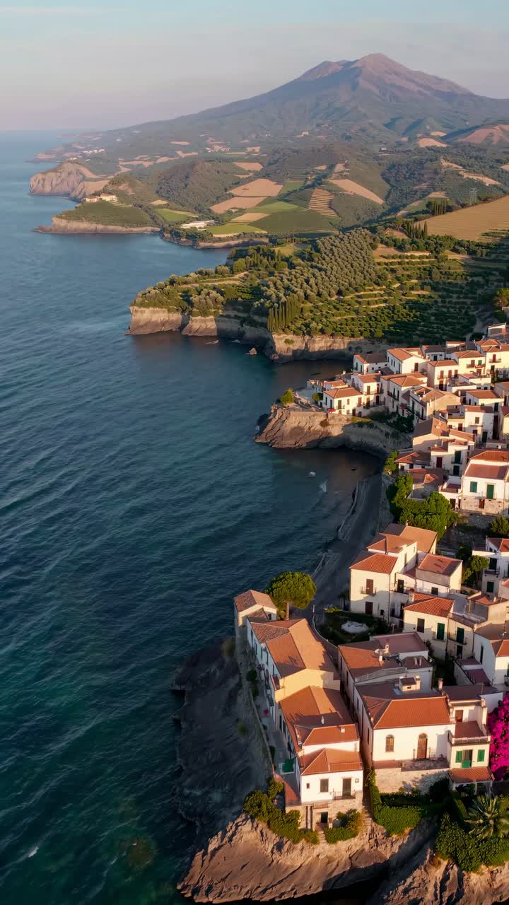 Aerial video captures a coastal village with colorful houses on cliffs, overlooking the sea