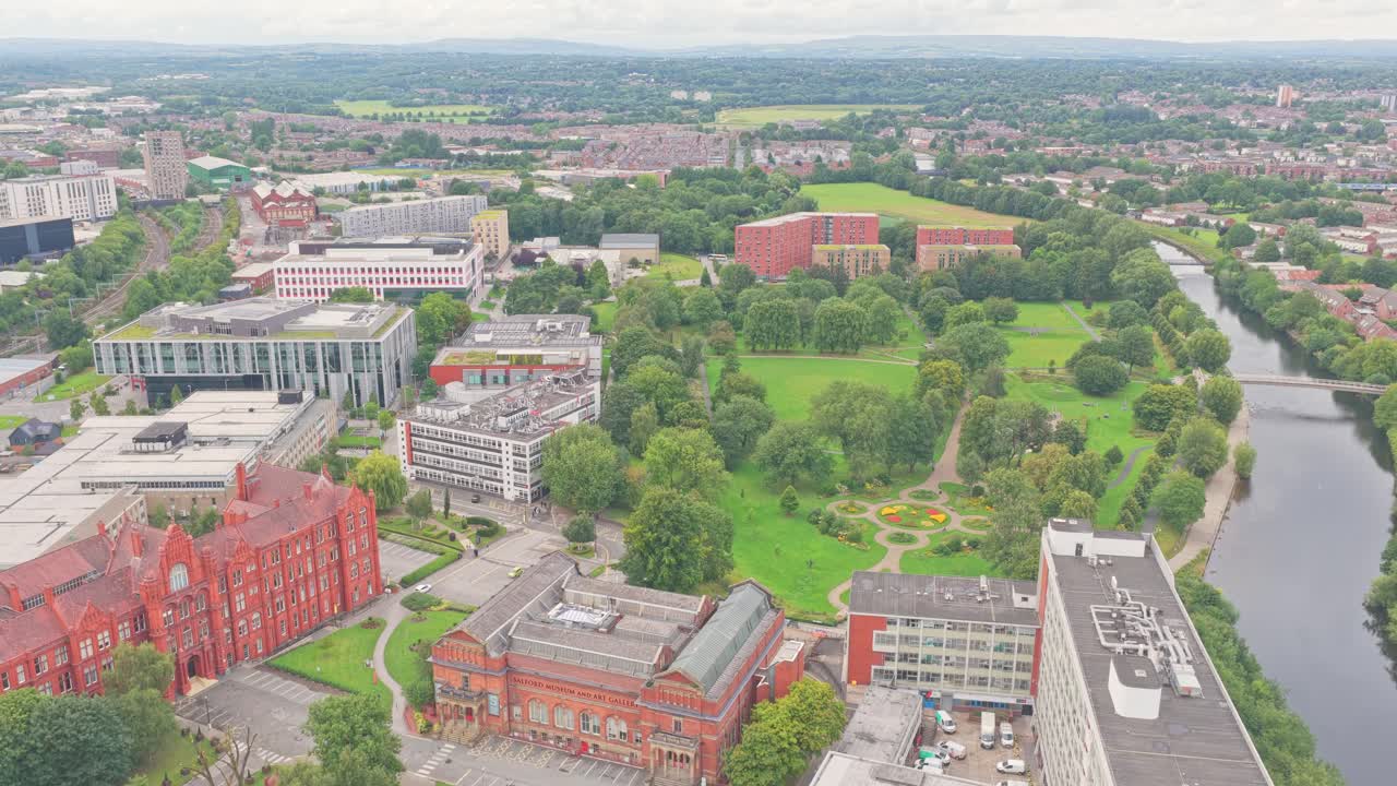 Aerial view over Salford Crescent showing the University of Salford campus, Peel Building, New Adelphi, Maxwell Building, Peel Park, student residences, and the River Irwell flowing alongside