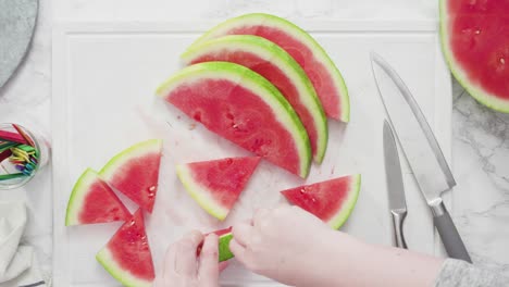 cortar la sandía roja en pedazos pequeños en una tabla de cortar blanca.