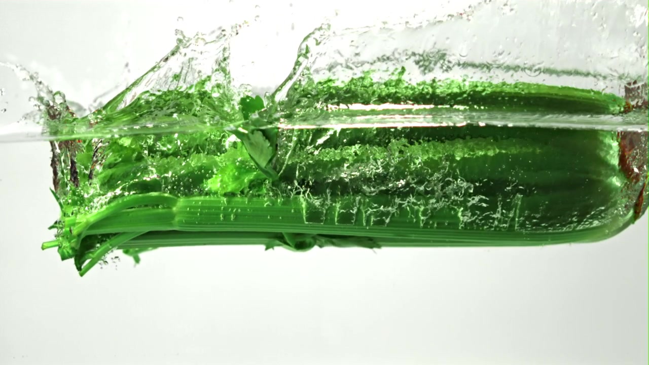 Fresh Green Celery Splashing into Clear Water in Slow Motion