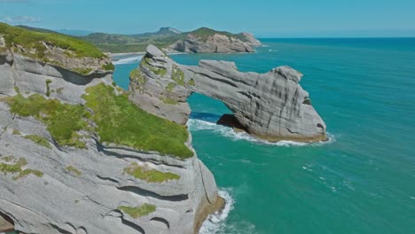 reverse aerial revealing scenic wharariki beach and unique rocky outcrops in the tasman sea at cape farewell, south island of new zealand aotearoa