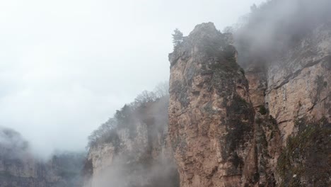 drone shot of steep rocks covered with dense fog