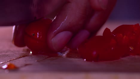 video de primer plano de las manos de un hombre cortando tomates cherry en una tabla de cortar