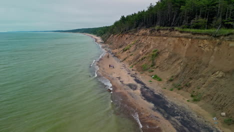 People-Walking-Along-The-Seashore-Of-Jurkalne-Beach-With-Bluffs-In-Latvia