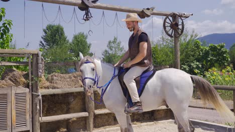 the man riding his horse on the farm. attractive white horse.