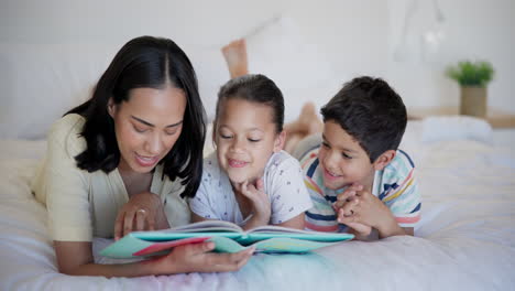 mother reading a book to her children on a bed