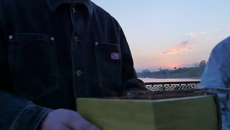 person burning wood by the river at sunset