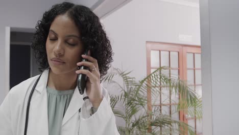 Portrait-of-biracial-female-doctor-wearing-lab-coat,-talking-on-smartphone,-copy-space,-slow-motion