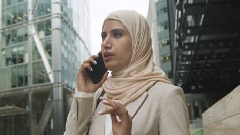 muslim businesswoman on mobile phone standing outside office in city 6