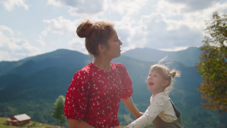 happy mother jumping daughter dancing on mountain hill close up. summer holiday.