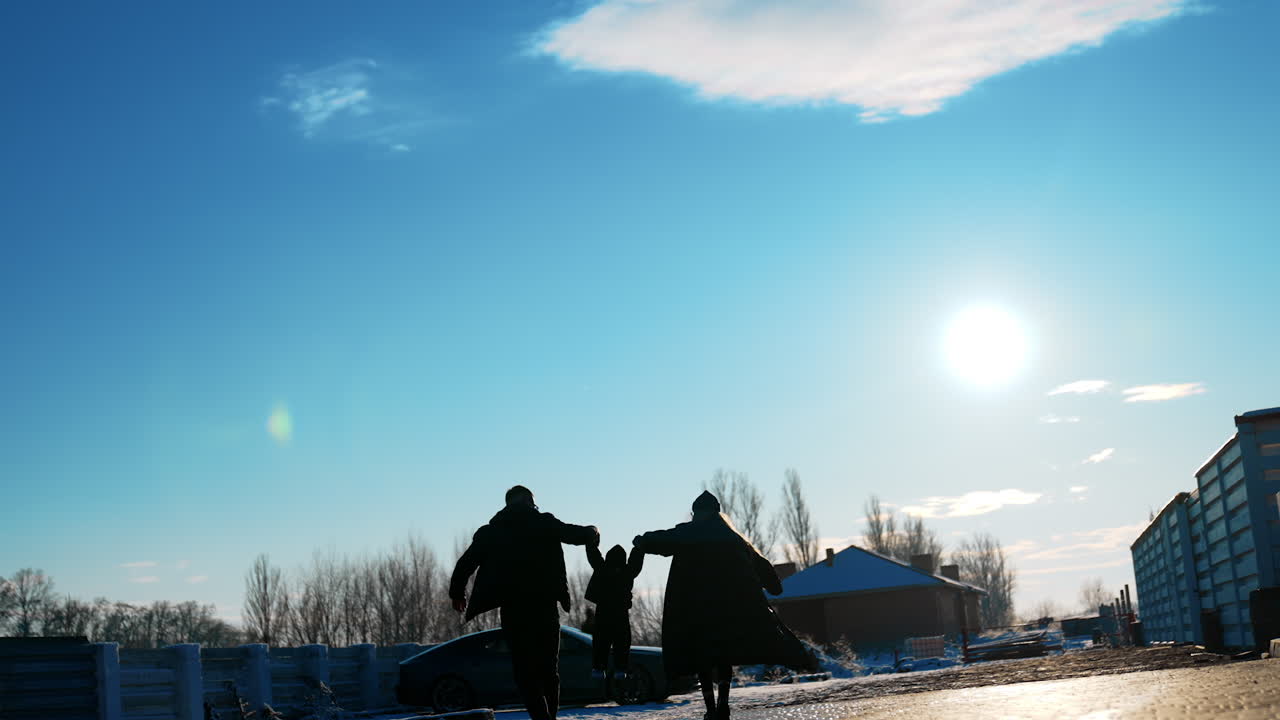Mom, dad and little son walk holding by the hands. Parents walking to the car raise their kid up. Low angle view.