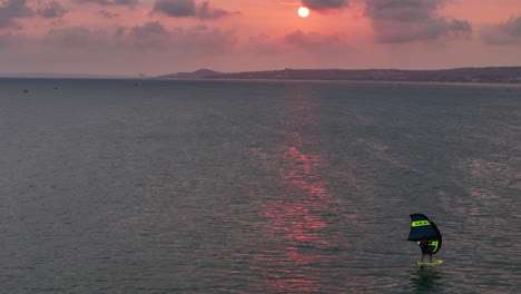 el ala del windsurfista se desliza a través de un cielo rosado al atardecer en la bahía de mui ne, phan thiet, vietnam