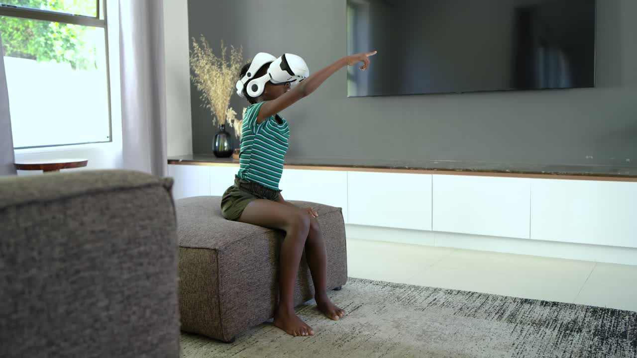 VR headset powering on, child reaching, sweeping arms on ottoman at home to grab virtual objects