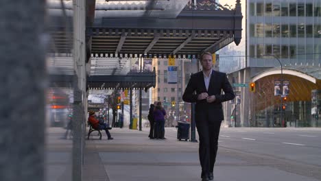 a young business man adjusts his suit as he walks through vancouver's downtown core