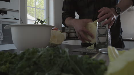 Closeup-of-man's-hand-grating-cabbage-for-fermentation-process,-sliding,-day