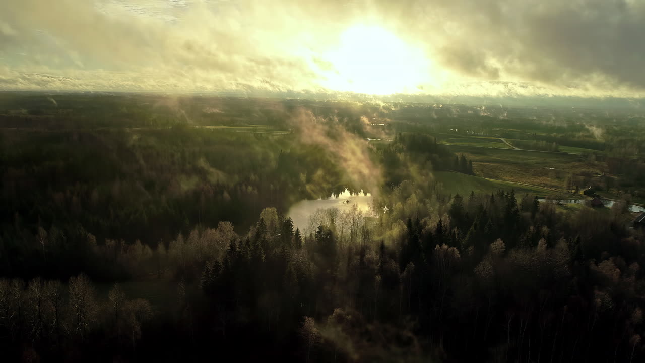 일출 동안 시골의 안개 낀 구름 뒤에 햇빛