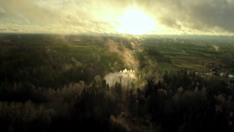 sunlight behind misty clouds over countryside during sunrise