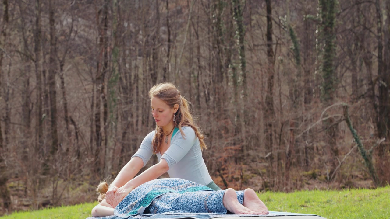 A female massage therapist practices holistic bodywork on a client in a serene forest meadow. Ideal for wellness, alternative medicine, and ecofriendly health content.